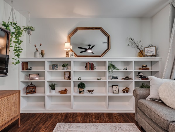 Una sala de estar con un estante blanco, un reloj y un sofá.
