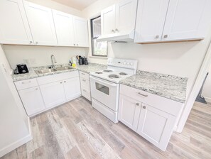 Eine moderne Küche mit weißen Schränken, einer Granitabdeckung, einem eingebauten Ofen und einer Edelstahl-Spüle.