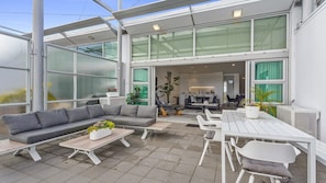 Ein Terrassenbereich im Freien mit einer Eckcouch, einem Esstisch und Stühlen.