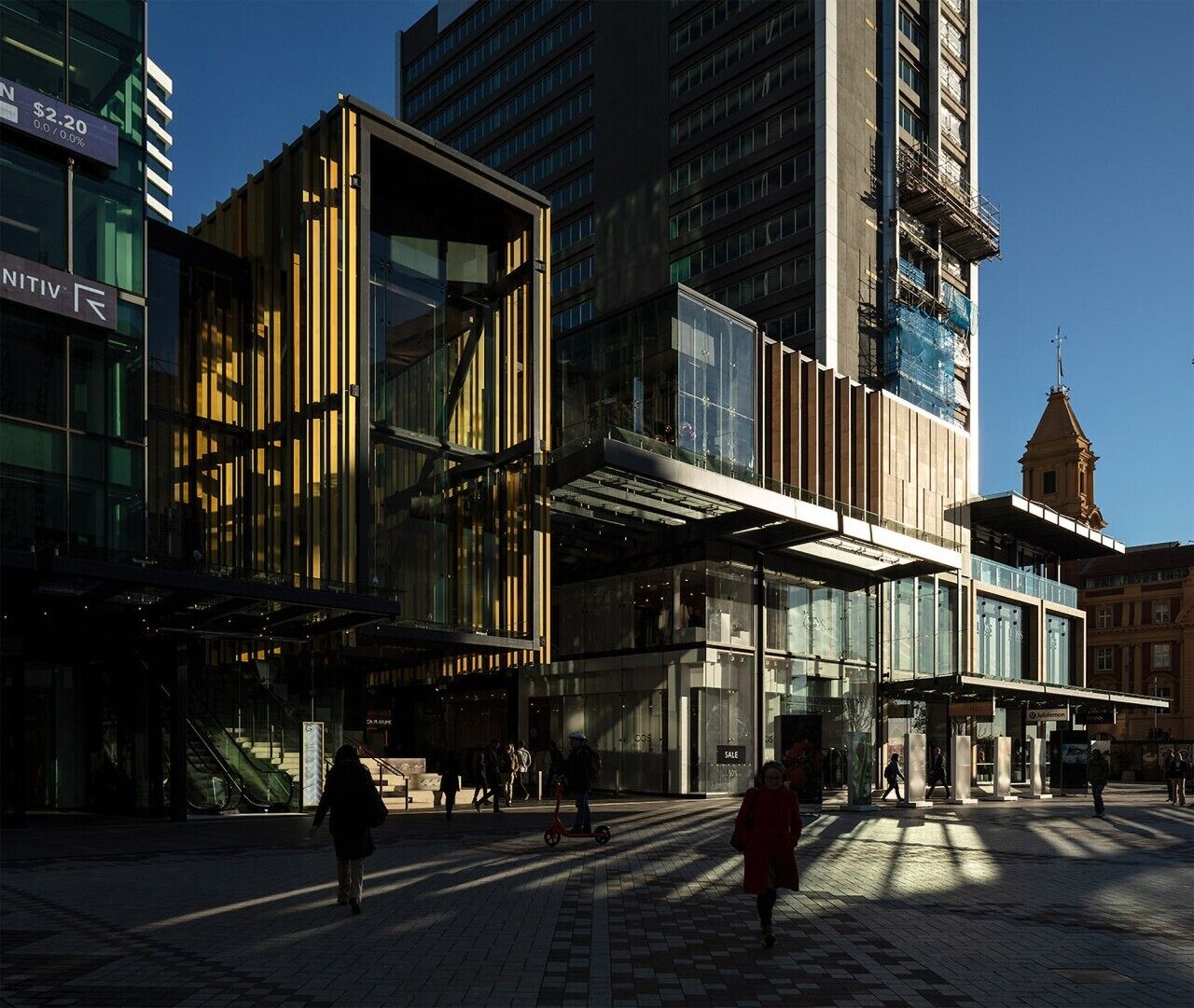 Un edificio moderno con fachada de vidrio, un acceso cubierto y una escalera visible.
