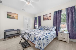 Ein Schlafzimmer mit Bett, Nachttisch, Schreibtisch und einem Fenster mit Vorhängen.
