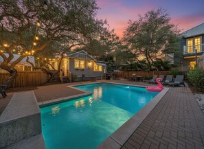 Ein Garten mit Pool, einer Holzterrasse und einem Haus mit Veranda.
