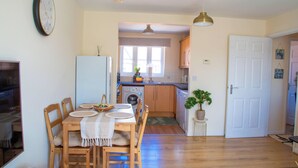 Cocina compacta con lavadora, mesa de madera y sillas, y una puerta blanca.