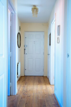 A hallway with wooden flooring, a white door, and a chandelier. - Spacious Accommodation Near NEC & Birmingham Airport (Solihull)