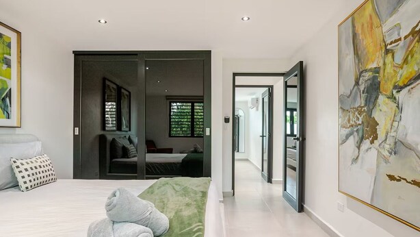 A modern bedroom with a bed, a green rug, and a large abstract painting. - Luxury Casa Kiarita • House on the Hill (San Juan)