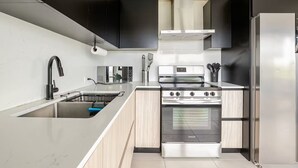 A modern kitchen with a stainless steel sink, a built-in oven, and a refrigerator. - Luxury Casa Kiarita • House on the Hill (San Juan)