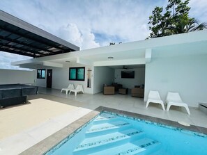 A modern outdoor pool area with a built-in pool, white lounge chairs, and a covered seating area. - Luxury Casa Kiarita • House on the Hill (San Juan)