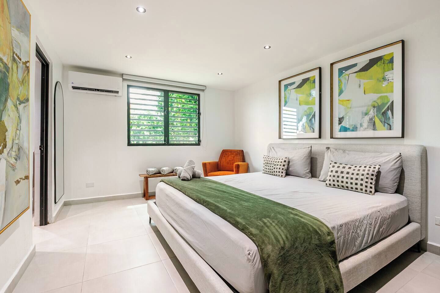 Ein Schlafzimmer mit Bett, Stuhl, Fenster und Bildern an den Wänden.