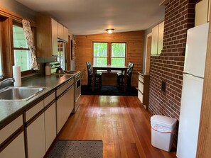 Une cuisine avec des meubles de rangement en bois, un évier, une cuisinière et une table à manger avec des chaises.