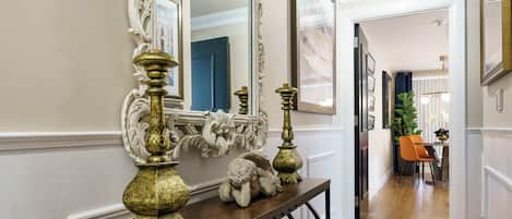 A hallway with a wooden console table, ornate mirrors, and a staircase leading to a dining area.
