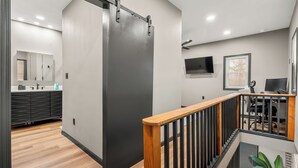 Ein modernes Interieur mit einer Schiebetür, einer Treppe mit Holzwertkasten, einem Flachbildfernseher und einem Schreibtisch mit Stuhl.