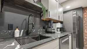 Eine moderne Küche mit Spüle, Kaffeemaschine, Mixer und Kühlschrank.