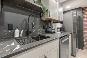 Ett modernt kök med en inbyggd diskho, en kaffebryggare, en mixer och ett kylskåp.