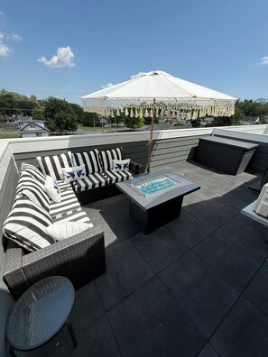 An outdoor seating area with a sofa, a table, and an umbrella.