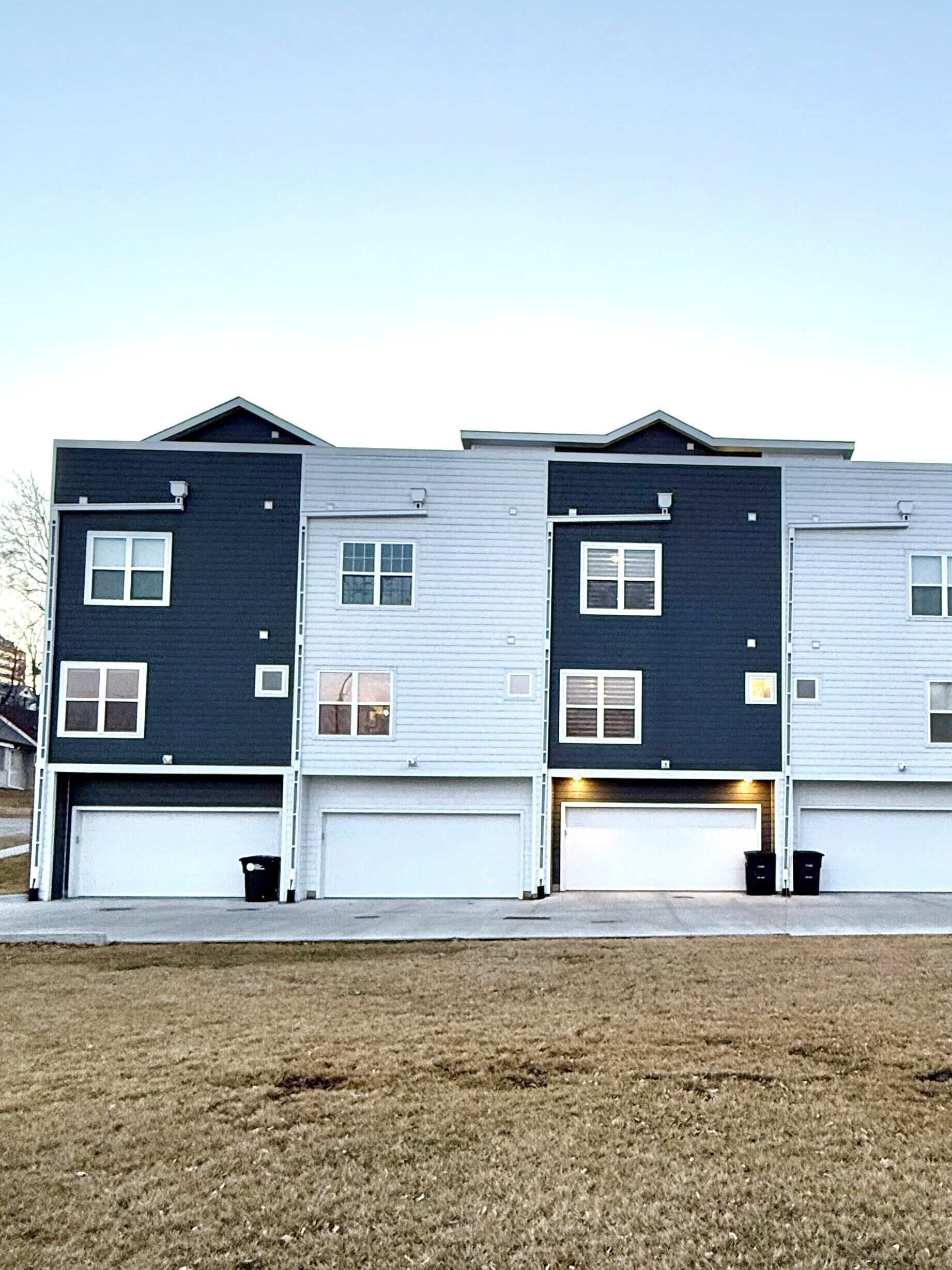 A two-story residential building with a garage on the ground floor and a driveway leading to the entrance.