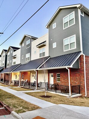 A row of townhouses with attached garages, a brick facade, and a clear sky.