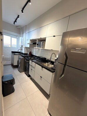 A modern kitchen with stainless steel appliances, white cabinetry, and a window providing natural light.