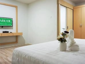 A hotel room with a bed, a wooden floor, a wall-mounted TV, and a wooden wardrobe. - Sovrano Hotel Batam (Batam)