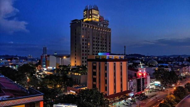 A high-rise building with multiple floors, surrounded by other buildings and a cityscape at dusk. - Sovrano Hotel Batam (Batam)