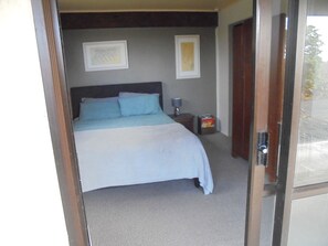 A bedroom with a bed, a nightstand, a lamp, and two framed pictures on the wall.