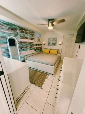 Ein Schlafzimmer mit Bett, Deckenventilator, Wandklimaanlage, einem Gemälde und einem weißen Kleiderschrank.