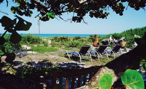 A beachside area with sun loungers and a rustic outdoor seating area.
