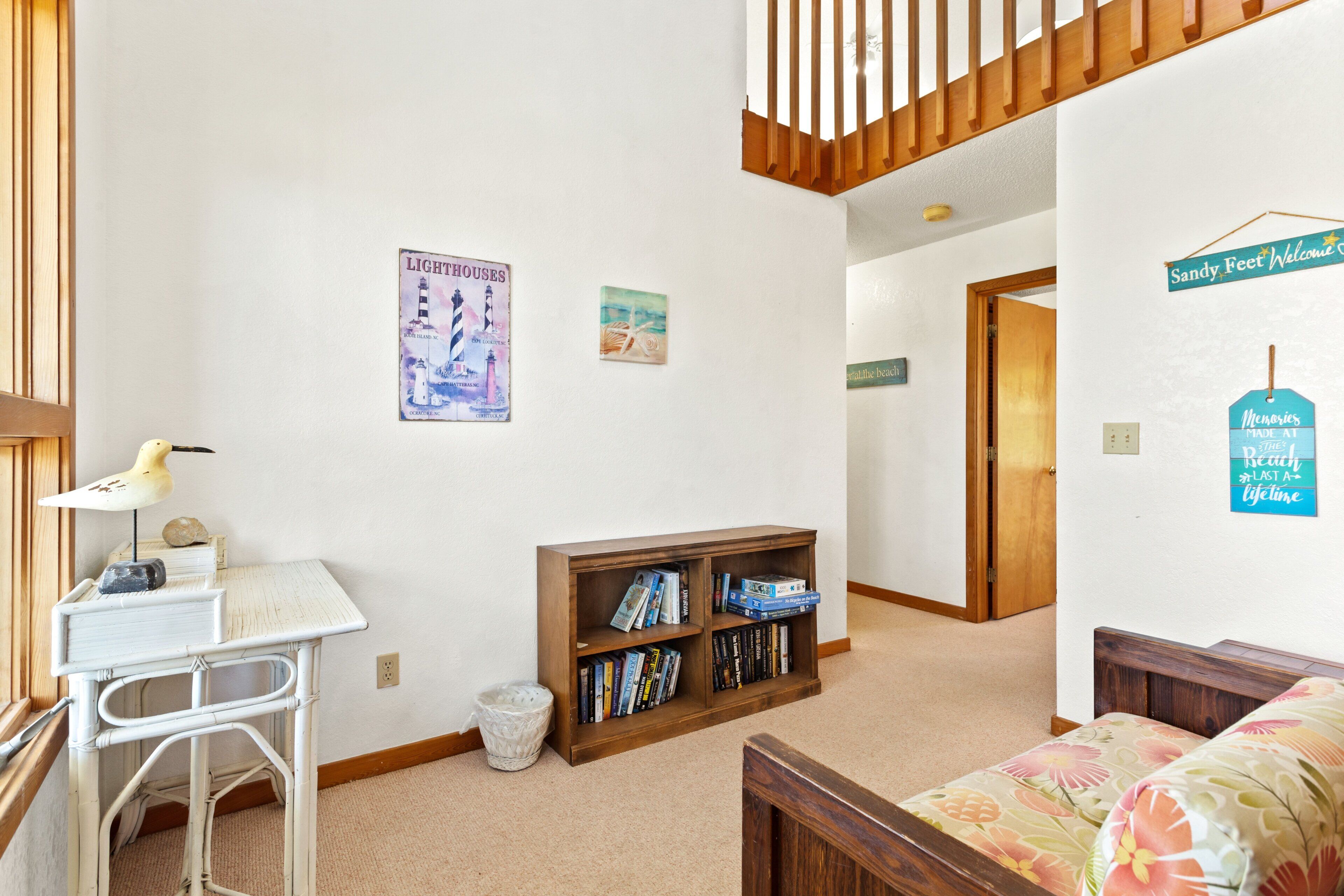A room with a desk, bookshelf, bed, and a staircase.