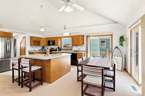 Eine geräumige Küche mit Holdekor-Schränken, einer zentralen Kochinsel und einem Essbereich mit gestreiften Stühlen.