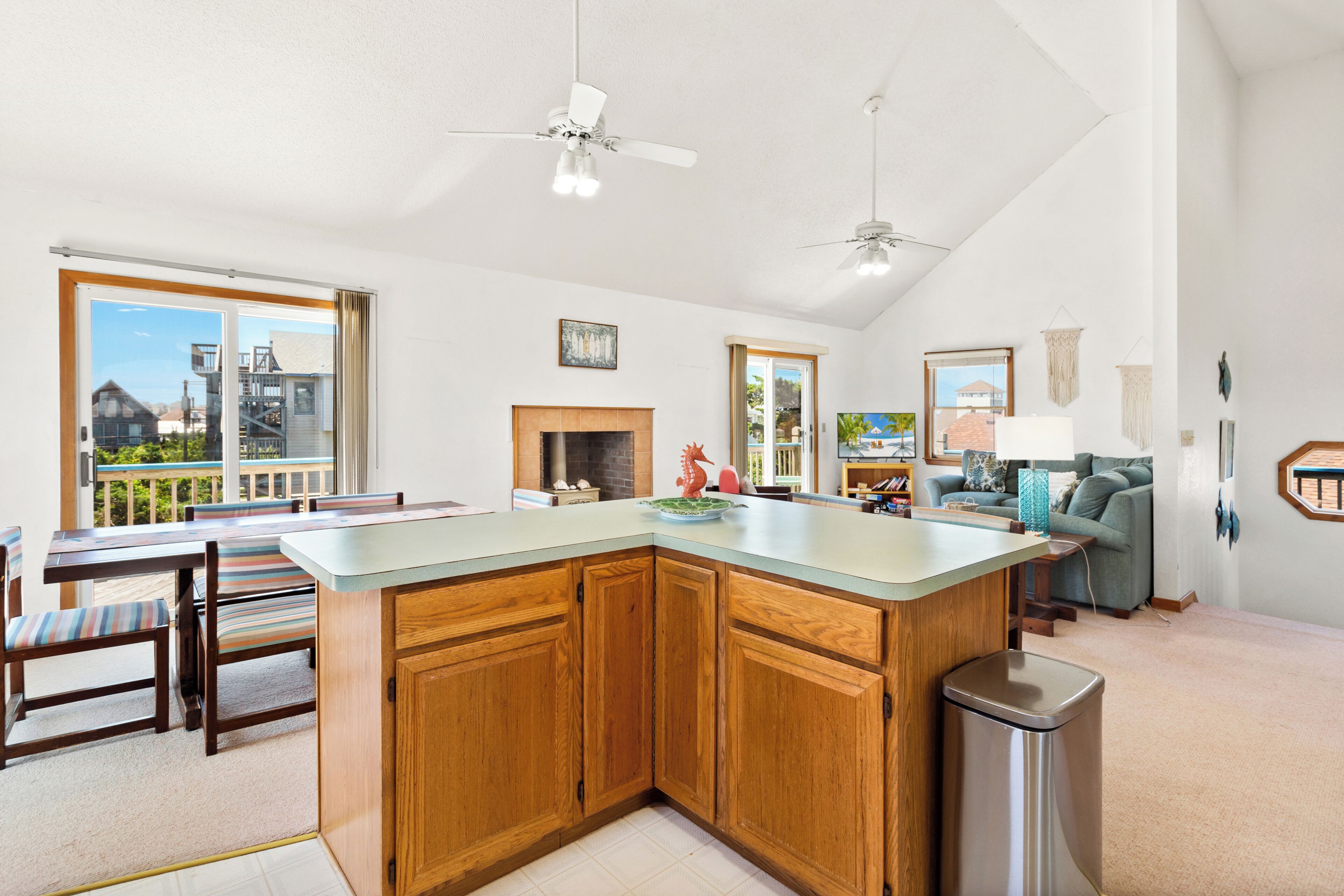 A modern kitchen with wooden cabinets, a central island, and a dining area with striped chairs.