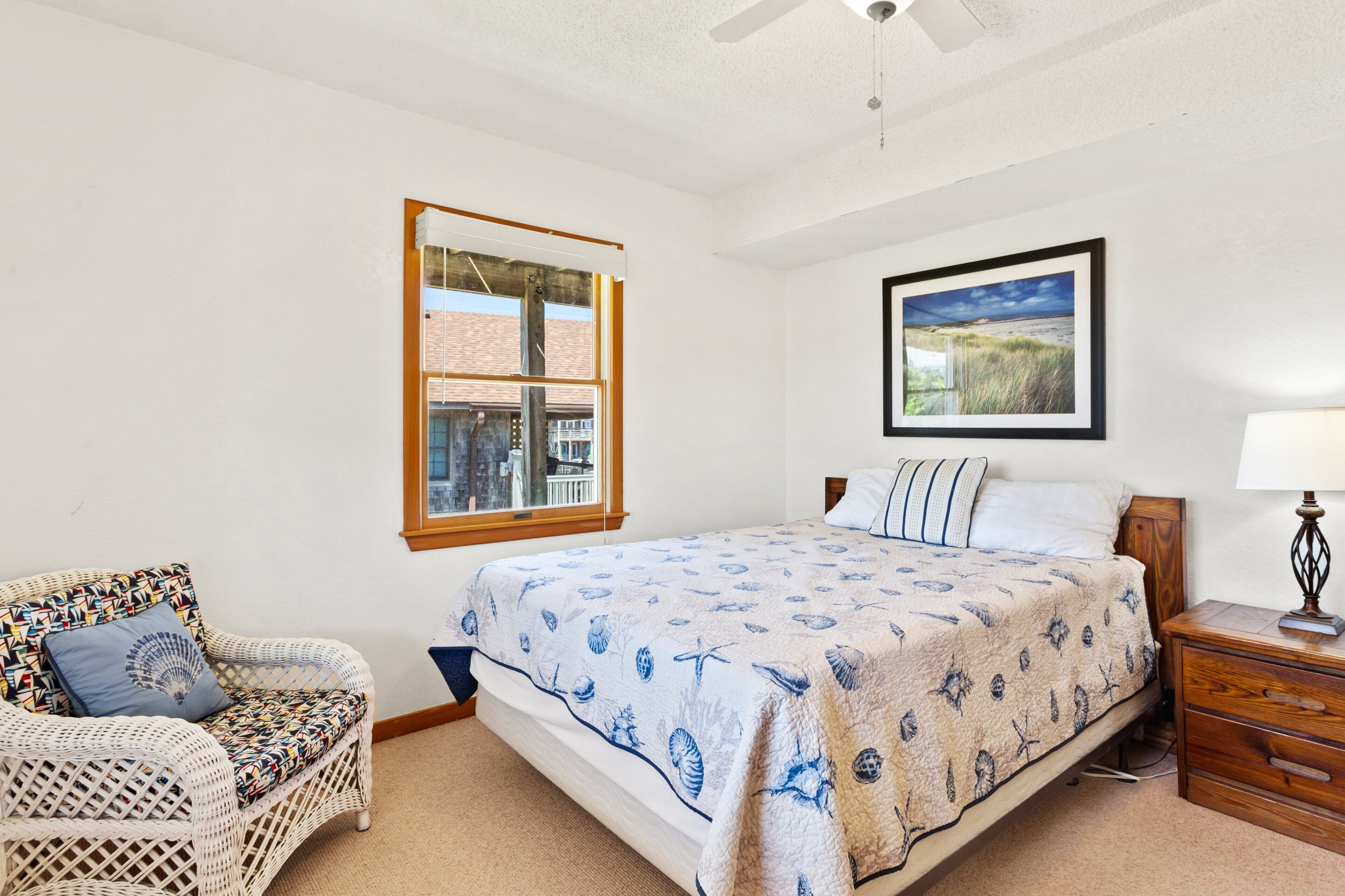 Une chambre à coucher comprenant un lit, une chaise, une fenêtre, un tableau accroché au mur et une table de chevet.