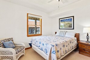 A bedroom with a bed, a chair, a window, a wall-mounted picture, and a bedside table. - White Dune: Dogs Allowed, Basketball Goal, Easy Beach Access (Avon)
