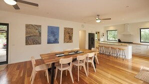 Una cocina moderna con una mesa de comedor de madera, taburetes de bar y un ventanal grande.