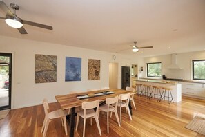 Une cuisine moderne avec une table à manger en bois, des tabourets de bar et une grande fenêtre.