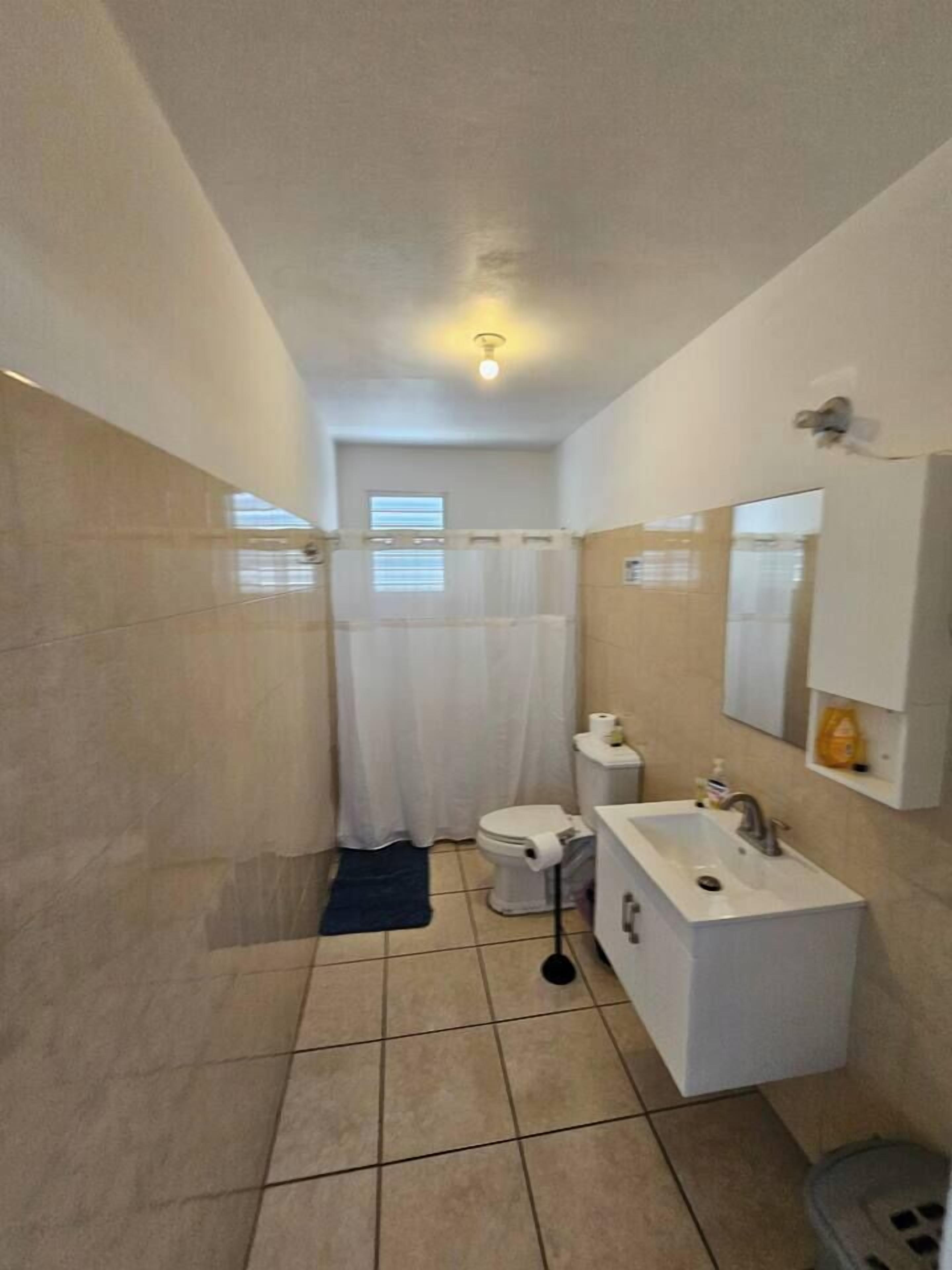 Een badkamer met toilet, wastafel en douchegordijn.