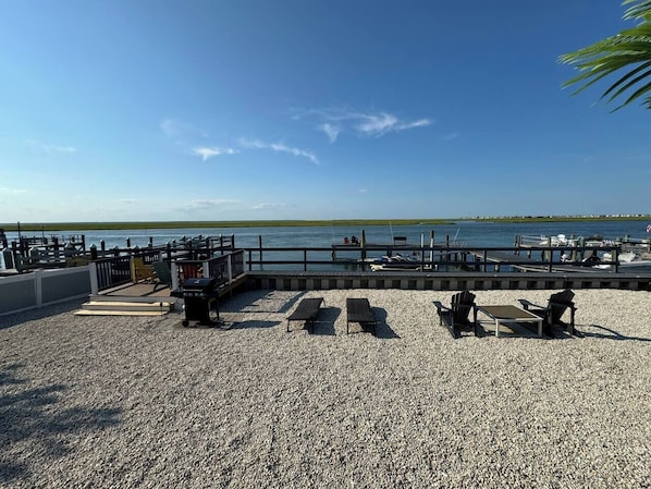 Eine Terrasse mit Kies und Gartenmöbeln, mit Blick auf das Wasser.