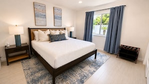 A bedroom with a bed, nightstands, a lamp, a window with curtains, and artwork on the wall. - New - Sleeps 10 Private Pool and Fenced Yard (Orlando)