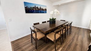 A dining area with a wooden table and chairs, a cityscape painting, and a potted orchid. - New - Sleeps 10 Private Pool and Fenced Yard (Orlando)
