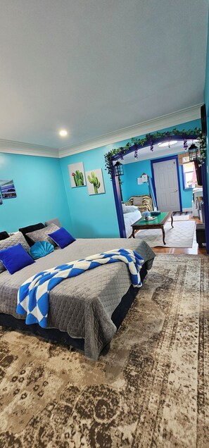 A bedroom with a bed, a nightstand, a dresser, and a door leading to another room.