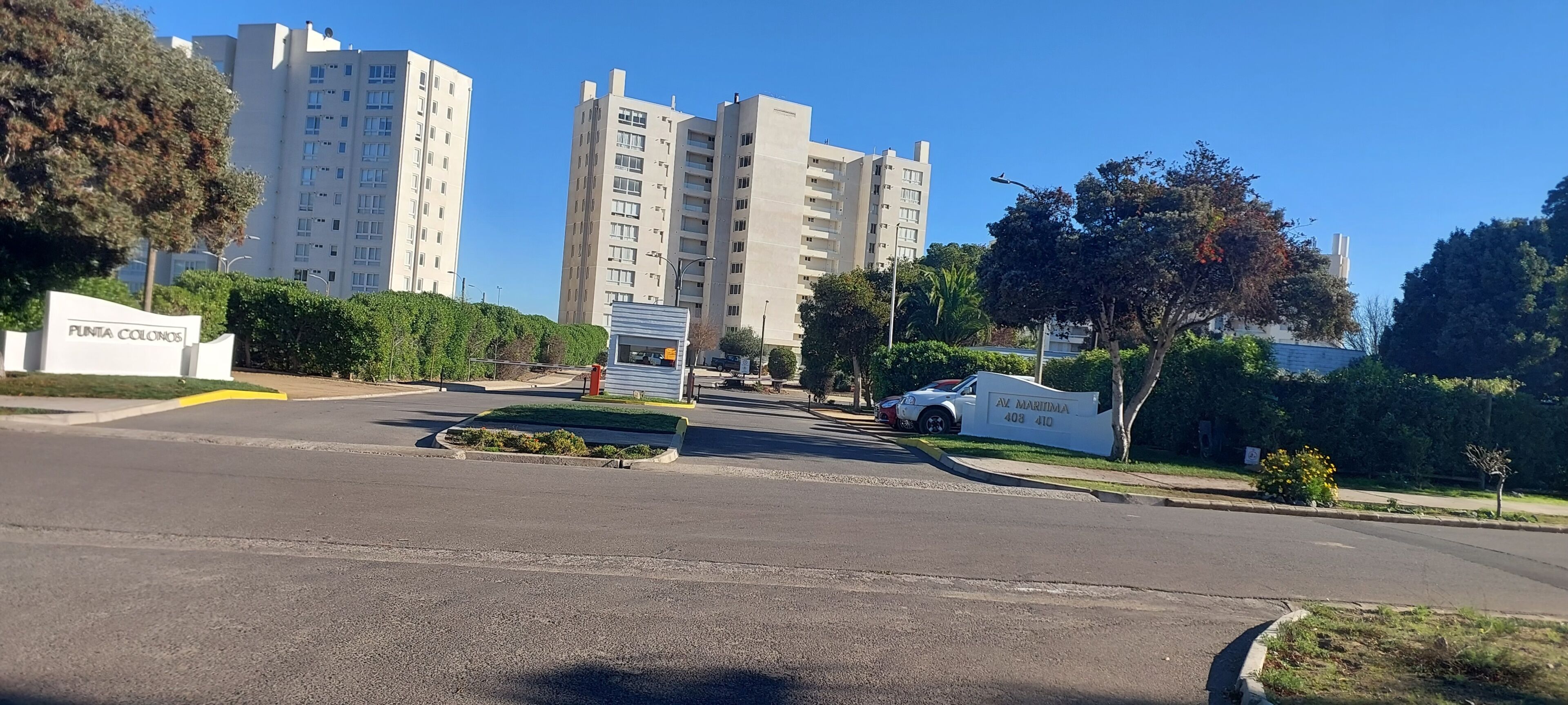 Zona residencial con edificios de apartamentos, una calle y un cartel que indica 'PUNTA COLONIOS'.