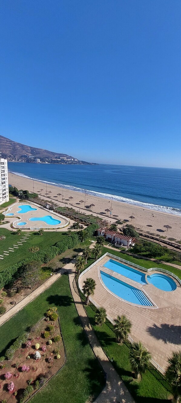 Ein Resort mit mehreren Schwimmbecken, einem Strand und einer Bergkulisse.