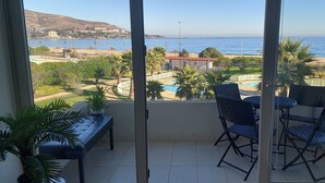 Un balcón con vistas al mar, una piscina y un edificio al fondo.