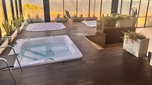 A spa area with two hot tubs, seating, and potted plants.