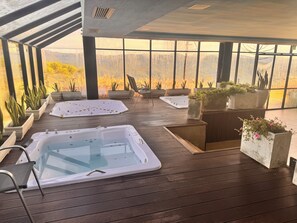 A spa area with two hot tubs, seating, and potted plants.