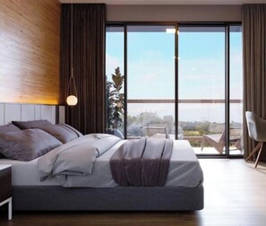 A modern bedroom with a large bed, a nightstand, a chair, and a view of the outdoors through large windows.
