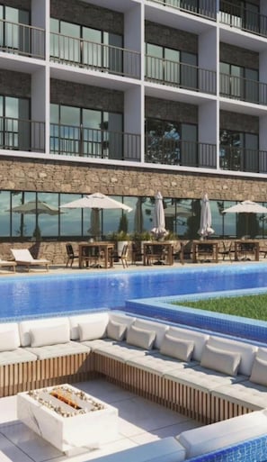 A hotel with a pool area, outdoor seating, and a stone facade.