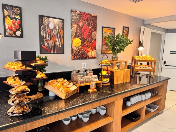 A buffet with various food items and a wall with framed artwork.