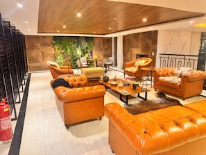 A modern living room with leather sofas, a coffee table, and a green wall with plants.