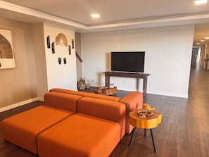 A living room with a sectional sofa, a wooden coffee table, and a TV on a stand.