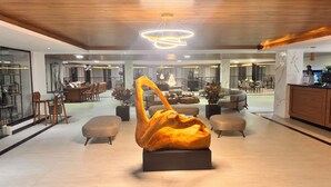 A spacious lobby with a modern chandelier, seating areas, and a central sculpture.