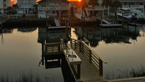 A waterfront property with a dock, a boat, and a sunset. - Johnson's Coastal Cottage (Ocean Isle Beach)